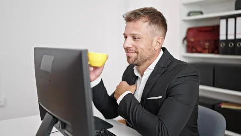 Young man business worker using computer drinking coffee at office Stock Footage 247379022