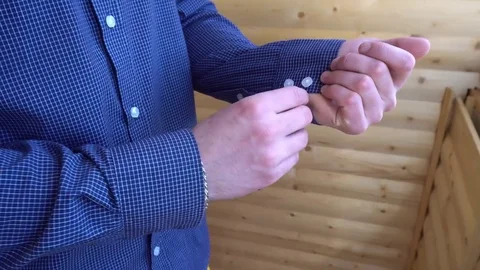Young man buttoning on the sleeves of the blue shirt Stock Footage 75211066