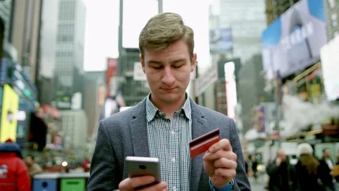 Young man buying something over the Internet on Times Square Stock Footage 79539777