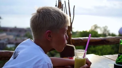 A young man in a cafe drinking a cocktail on terrace. outdoors 動画素材 75052981