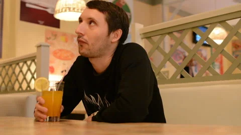 A young man in a cafe drinking lemonade Stock Footage 88834386
