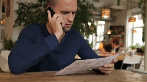 Young man in cafe or restaurant, looking through the menu talking phone Stock Footage 67862042
