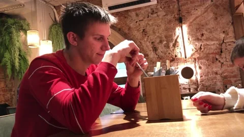 Young man in a cafe in a red sweater, smiles and listens to the interlocutor. Stock Footage 226209376