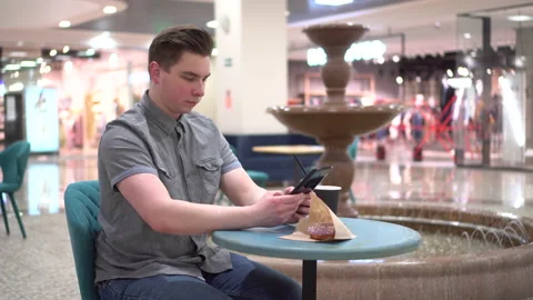A young man in a cafe with a tablet in his hands against the background of a Stock Footage 152487595