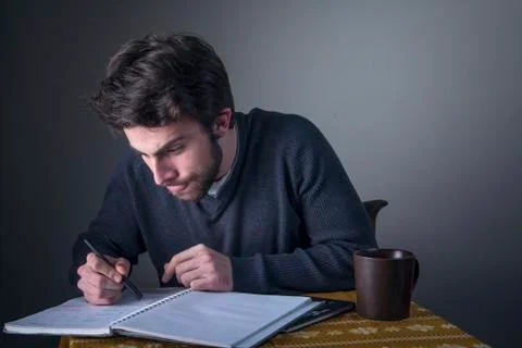 Young man calculating, writing down and studying Stock Photos