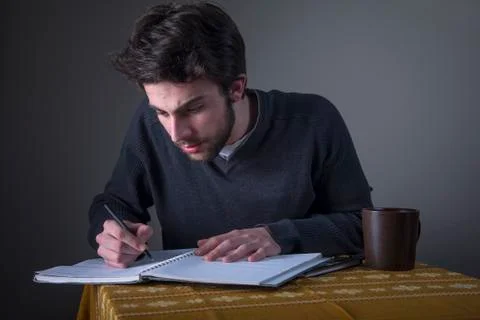 Young man calculating, writing down and studying Stock Photos