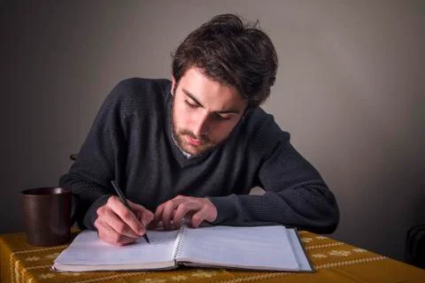 Young man calculating, writing down and studying Stock Photos