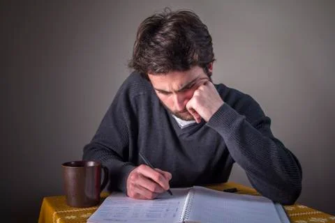 Young man calculating, writing down and studying Stock Photos