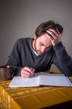 Young man calculating, writing down and studying Stock Photos