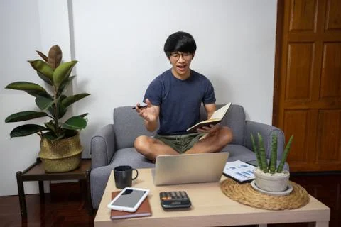 Young man calling with customer on the sofa or speak talk on video call with Stock Photos