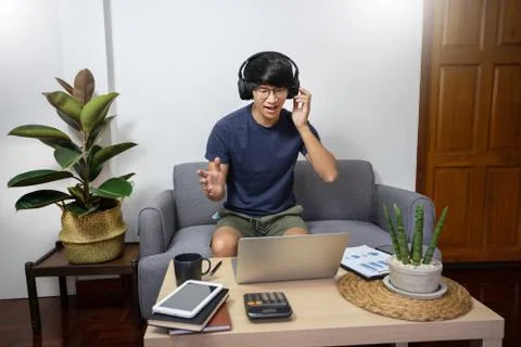 Young man calling with customer on the sofa or speak talk on video call with Stock Photos