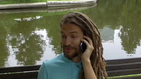 A young man calling on the phone in the park Stock Footage 65330113