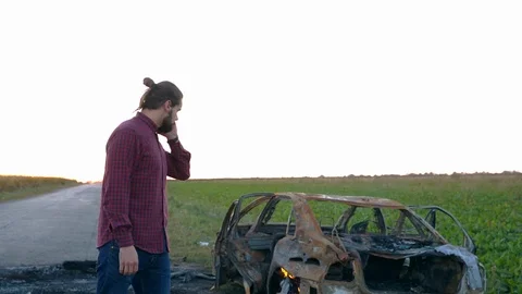 A young man calls a fire brigade in the countryside standing on the background Stockbeeldmateriaal 112712702