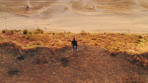 A young man with a camera in his hand is standing on the edge of the sea shor Stock Footage 160121067