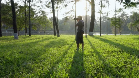 Young man with camera taking pictures in evening woods Stock Footage 88723965