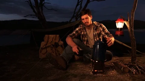 Young Man Camping Alone Making Coffee on a Camp Fire at Night Stock Footage 127189525