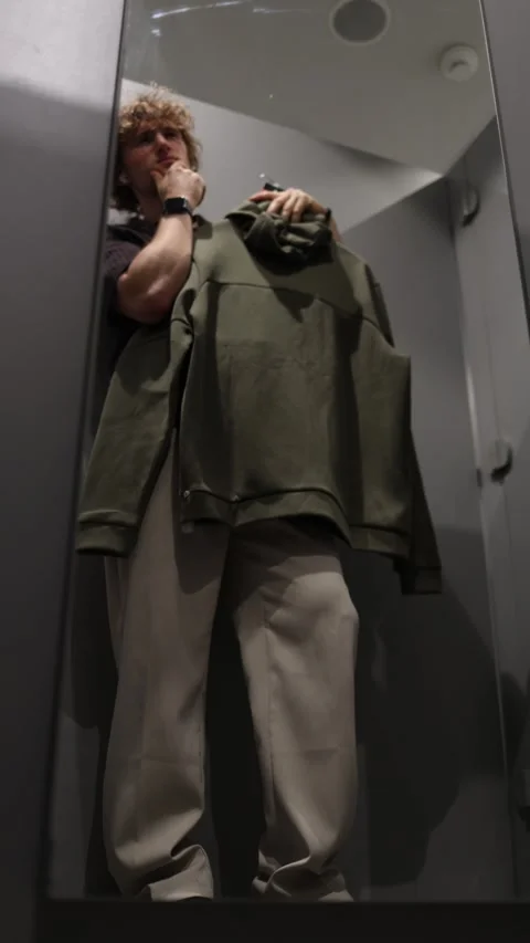Young man cannot find the right clothing item while choosing clothes Stock Footage 344854737