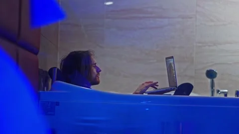 The young man cannot leave his laptop even lying in the bathtub, he has to wash Stock Footage 252274123