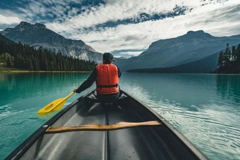 Young Man Canoeing on Emerald Lake in the rocky mountains canada with canoe and Stock Photos