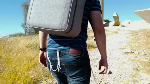 Young man with cap and backpack climbing a hill in a public park, a sunny day. Stock Footage 135430632