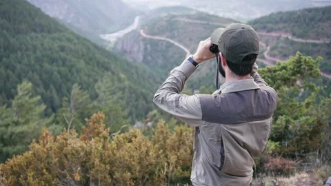 Young man with cap and uniform holds binoculars and looks into the distance Stock Footage 241737581