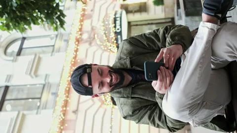 Young Man In Cap With Beard Sitting On The Street With Phone In His Hands. He Stock Footage 152024273