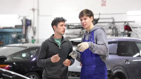Young man car mechanic talks with man client in workshop and takes order. Stock Footage 344776371