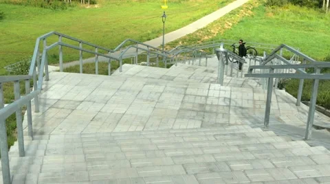 A young man carries a bicycle through the long stairs. Against the background of Stock Footage 66576567
