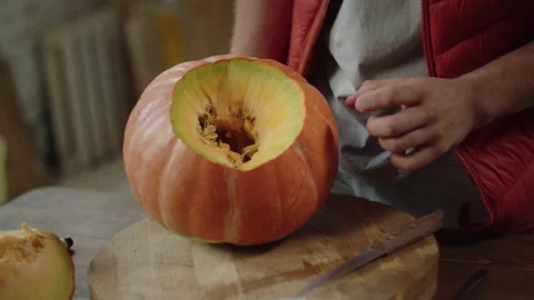 A young man carves the inside of a pumpkin and turns it Stock Footage 170519691