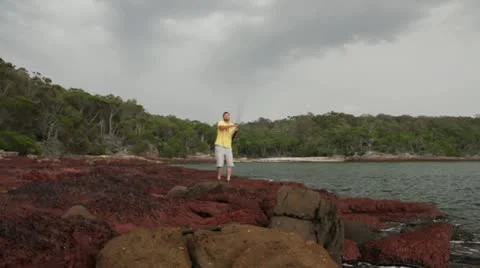 Young man casting off rocks while fishing at Bittangabee Bay, Australia Stock Footage 11286445