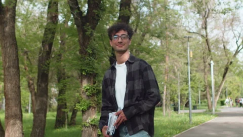 Young man in casual clothes with documents in his hands walking on an alley of Stock Footage 276170466