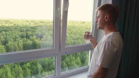 A young man in casual clothes drinking clean water while admiring the view of Stock Footage 209133523