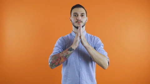 Young man in casual clothes standing with closed eyes in praying gesture. Wish Stock Footage 138572910