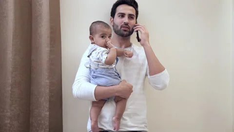 A young man in casual clothes talking on his mobile while standing in his room Video stock 169904102
