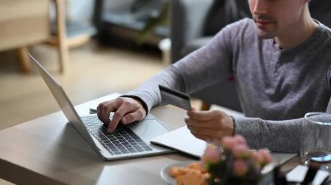 Young man in casual clothes using laptop computer for banking online or shopping Stock Photos