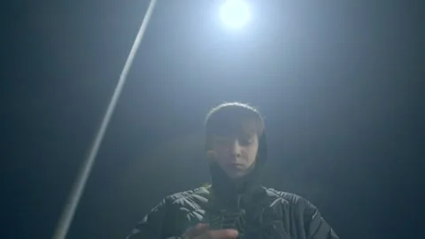A young man casually holds his phone under a streetlight in the evening Stock Footage 311205993