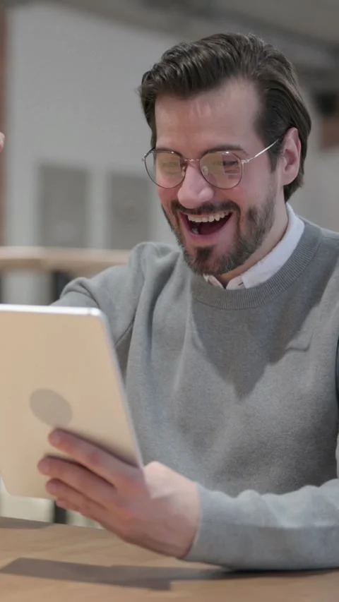 Young Man Celebrating Success on Tablet in Office, Vertical Video Vídeo Stock 339580952