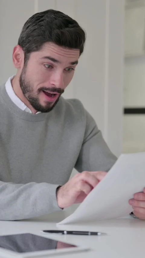 Young Man Celebrating Success while Reading Documents in Office, Vertical Video Video stock 339582399