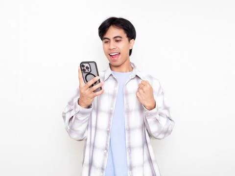 Young man celebrating while checking his smartphone, showing excitement abo.. Stock Photos