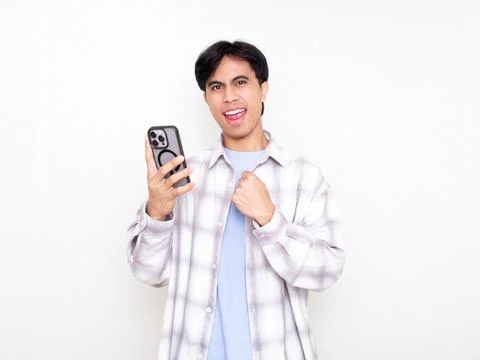 Young man celebrating while checking his smartphone, showing excitement abo.. Stock Photos