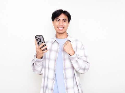 Young man celebrating while checking his smartphone, showing excitement abo.. Stock Photos