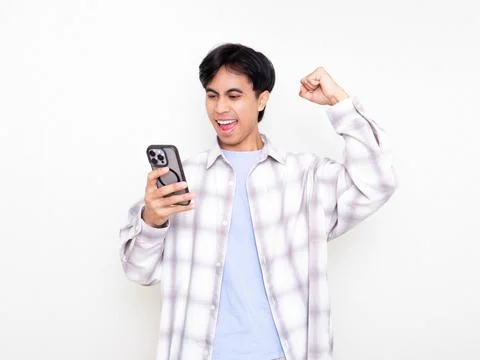 Young man celebrating while checking his smartphone, showing excitement abo.. Stock Photos