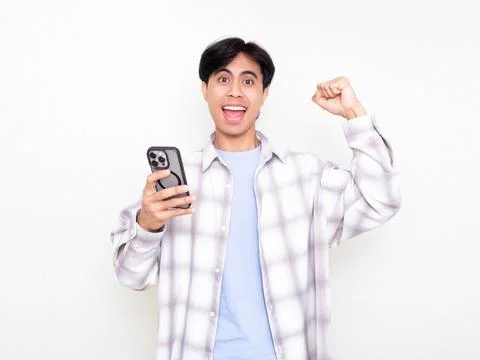 Young man celebrating while checking his smartphone, showing excitement abo.. Stock Photos