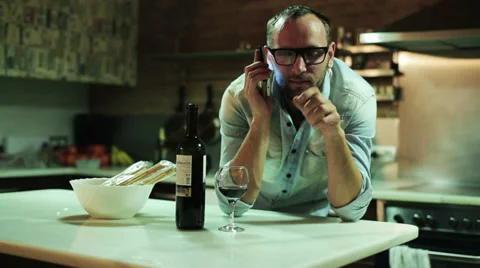 Young man with cellphone drinking red wine in his kitchen Stock-Footage 36632123