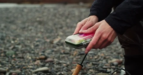 Young man changes his lure while fishing Stock Footage 102186609