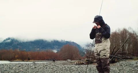 Young man changes his lure while fishing Stock Footage 102186833