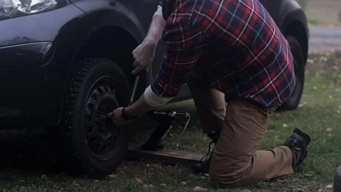 Young man changes tires for the first time, tightens lugnuts Stock Footage 97402734