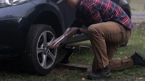 Young man changes tires for the first time Stock Footage 97403240