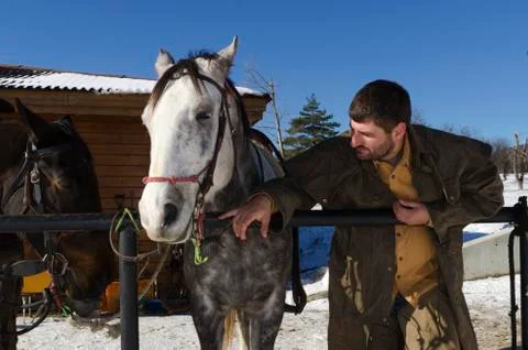 Young man with chaps and two horses in front of barn Stock Photos