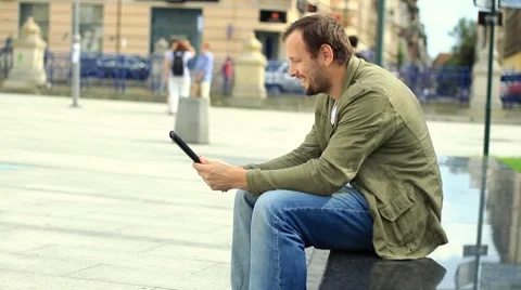 Young man chatting on tablet computer in the city HD Stock Footage 8524141